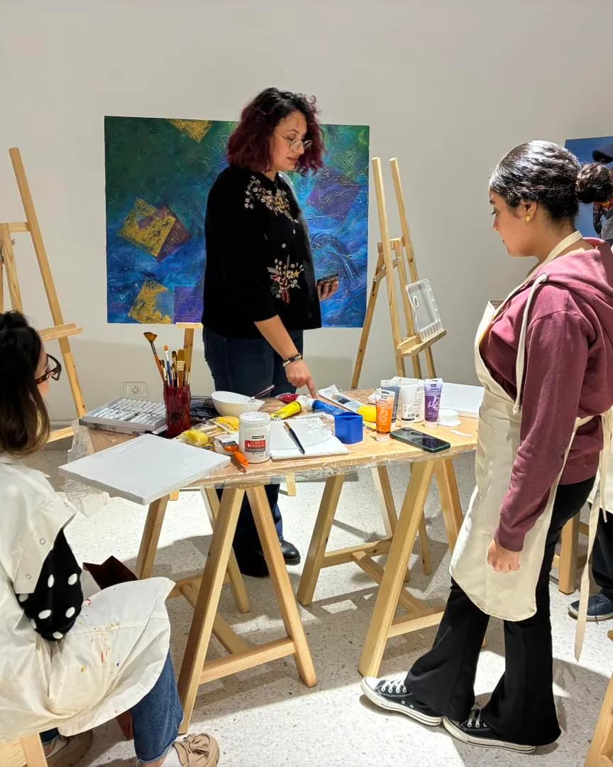 Instructrice présentant le matériel de peinture à des élèves devant des chevalets